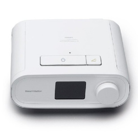 Balts Philips DreamStation CPAP aparāts ar displeja ekrānu, lielu apaļu ciparnīcu un ieslēgšanas pogu uz augšējā paneļa.