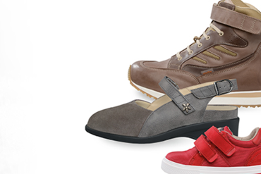 Uz balta fona ir parādīti trīs dažādi apavi: brūni augstpapēžu apavi, pelēki ortopēdiskie apavi ar sānu sprādzi un sarkani apavi ar divām velcro siksnām.